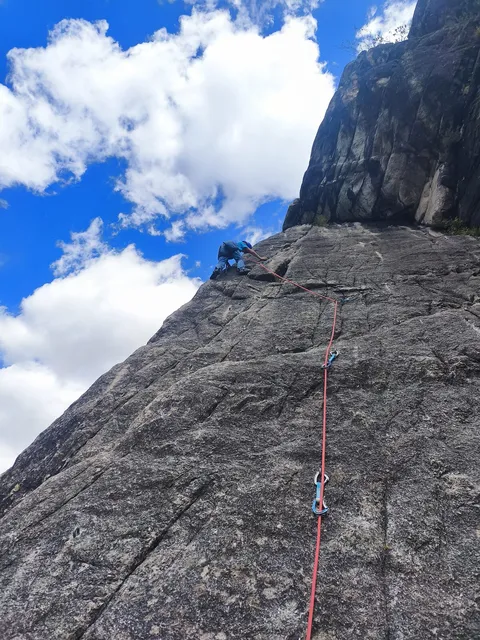 Grimpeur en grande voie sur une aiguille calcaire, ciel bleu