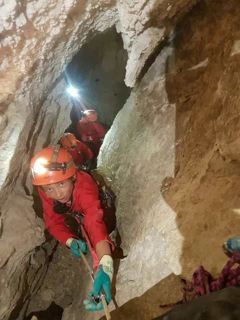 Spéléologue en combinaison avec éclairage frontal dans une galerie